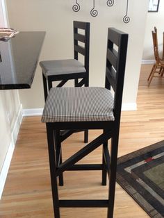 two black and white chairs sitting in front of a counter with an area rug on the floor