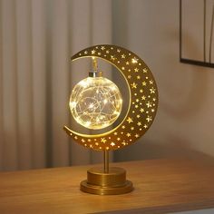 an illuminated moon and star decoration on a wooden table