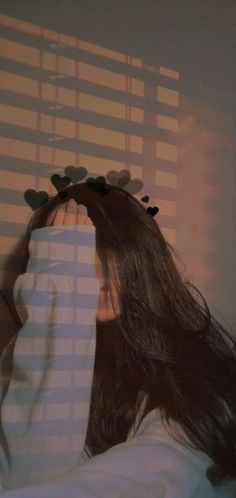 a woman covering her face with hair combs in front of a window covered by blinds