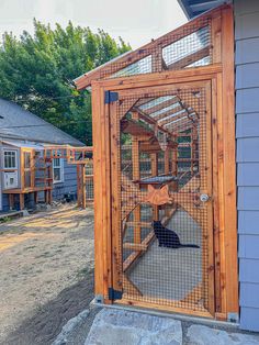 a small wooden structure with a cat in it's cage on the side of a house