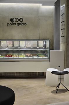 the interior of a deli with white chairs and black tables in front of it