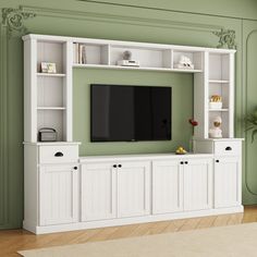 a living room with green walls and white entertainment center on the wall, along with a large flat screen tv