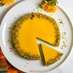 a piece of cheesecake on a white plate with yellow flowers and leaves around it