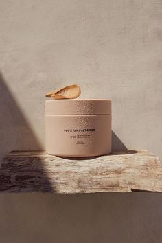 a white container sitting on top of a wooden table next to a wall and a shadow