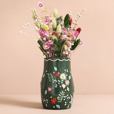 a green vase filled with lots of flowers on top of a white tablecloth covered floor