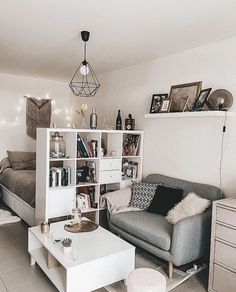 a living room filled with furniture next to a white table and bookshelf on the wall