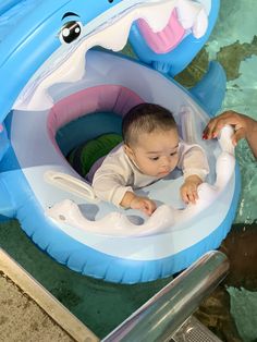 a baby sitting in an inflatable boat with its mouth open while being held by someone