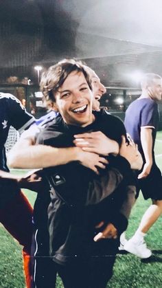 two men are hugging each other on the soccer field at night, one is holding his arm around the other's neck