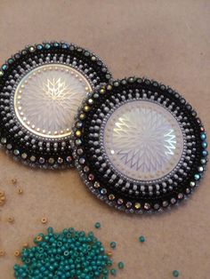 two beaded coasters sitting on top of a table next to beads and scissors