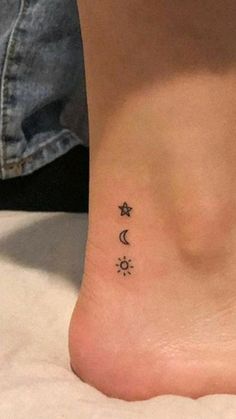 a woman's foot with three small stars and moon tattoos on the side of her ankle