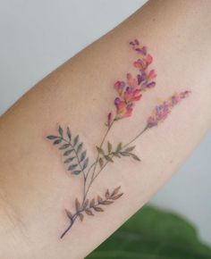 a close up of a person's arm with flowers on the left side of their arm