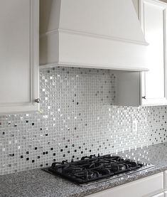 a stove top oven sitting inside of a kitchen next to white cabinets and counter tops