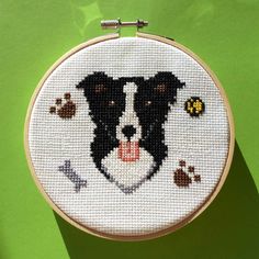 a black and white dog with paw prints on it's face in a cross stitch hoop