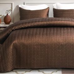 a bed with brown comforter and pillows in a room