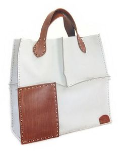 Nanan's trendy design exudes urban chic with a touch of safari vogue. The #leather #bag is tooled by hand featuring contrasting panels. These are placed on the top or the bottom of either side. Sturdy handles in the same shade complete the bag's refined allure. Beige Textured Leather Rectangular Satchel, White Box Bag With Top Handle And Leather Handles, Rectangular Leather Box Bag With Leather Handles, Leather Backpack With Leather Handles For Shopping, Leather Square Box Bag For Errands, Beige Rectangular Bag With Leather Lining, Soft Leather Box Bag For Everyday Use, Everyday Soft Leather Box Bag, Leather Double Handle Bags