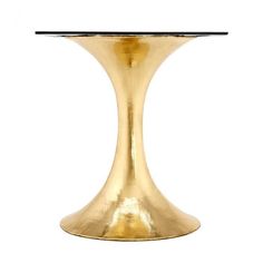 a gold pedestal table with a glass top and black base, on a white background