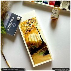 a bookmark with an image of a tree on it next to some paintbrushes