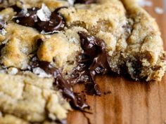 a chocolate chip cookie is cut in half on a cutting board with one bite taken out