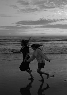 two women running on the beach with their hair blowing in the wind as the sun sets