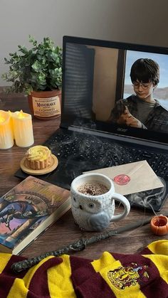 a laptop computer sitting on top of a wooden table next to candles and other items