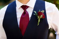 a man in a vest and tie with a boutonniere on his lapel