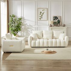 a living room with white furniture and wood floors