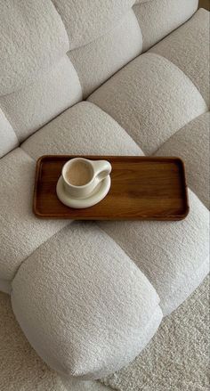 a tray with a coffee cup on it sitting on top of a white couch cushion