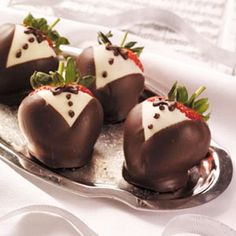 four chocolate covered strawberries on a silver plate