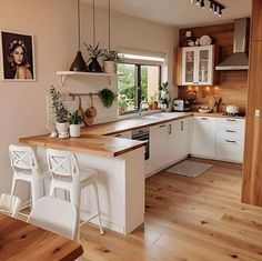 a kitchen with wooden floors and white cabinets is seen in this image from the dining room