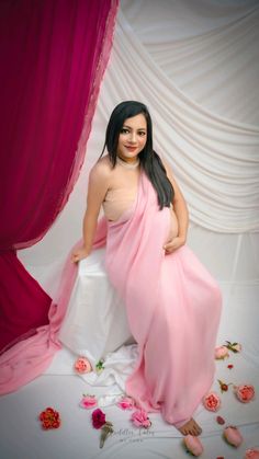 a woman in a pink sari posing for a photo with roses on the ground