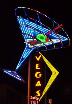 the neon sign for vegas is lit up at night