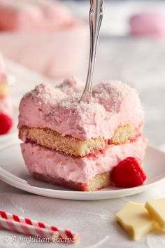 a piece of cake on a plate with a fork sticking out of it and raspberries in the background