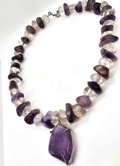 Amethyst and clear rock crystal beaded handcrafted artisan necklace. Stunning large natural tumbled crystals are strung on a thick memory wire. Large amethyst pendant is in the center of the necklace. Gemstones tested with Presidium II gemstone tester. Necklace measures a wearable 19.5 inches long. Pendant measures approx 1 and 1/2 of an inch tall and 1 and 1/8th of an inch wide. Spiritual Necklace With Large Mineral Crystal Stone, Clear Gemstone Necklaces For Healing, Beaded Amethyst Pendant Jewelry, Amethyst Beaded Pendant Jewelry, Handmade Amethyst Pendant Beaded Necklaces, Handmade Amethyst Pendant Beaded Necklace, Unique Amethyst Gemstone Beads Necklace, Amethyst Beaded Crystal Necklaces For Healing, Spiritual Clear Gemstone Necklace