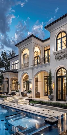 a large white house with a pool in the front yard and lots of windows on each side