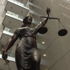 a statue of lady justice holding the scales of justice in front of a large building