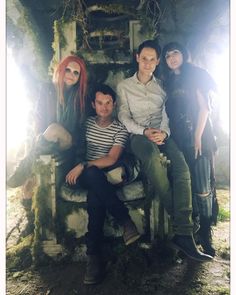 a group of people sitting on top of a bench in front of a tree stump