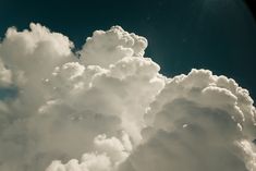 an airplane is flying high in the sky with clouds behind it and sun shining through the clouds