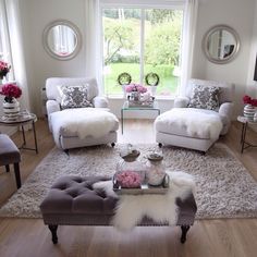 a living room filled with white furniture and lots of flowers in vases on the coffee table