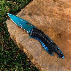 a blue and black knife sitting on top of a rock