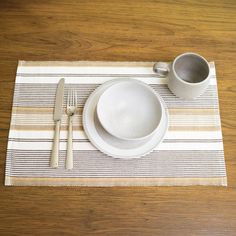 a place mat with a bowl, fork and spoon on it next to a cup