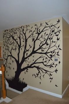 a tree painted on the side of a wall in a living room next to stairs