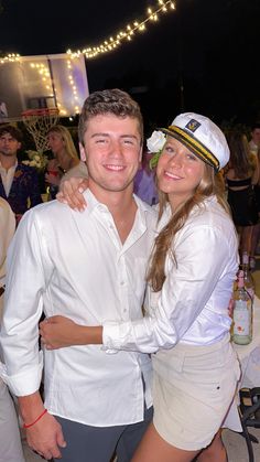 a man and woman are posing for a photo at an outdoor event with people in the background