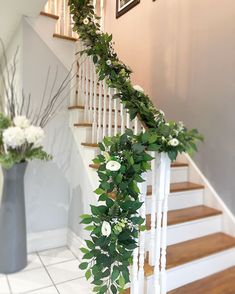 the stairs are decorated with greenery and white flowers