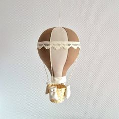 a hot air balloon ornament hanging from a string with lace on it's edge