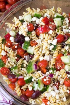 pasta salad with tomatoes, cucumbers and feta cheese in a glass bowl