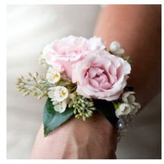 a woman's arm with a pink rose and white flowers on it, while wearing a wedding band