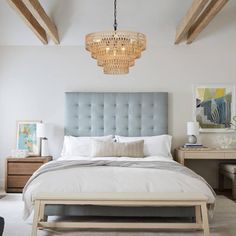 a bedroom with a large bed and chandelier hanging from the ceiling above it