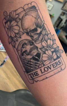 there is a tattoo on the arm of a person that has two skulls and flowers