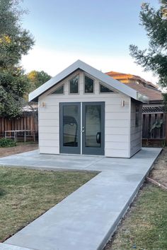 a small white shed sitting in the middle of a yard