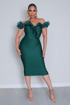 a woman wearing a green dress with ruffles on the shoulders and one shoulder